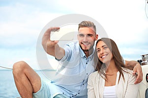 Happy couple in love taking selfie on sailing boat, relaxing on a yacht at the sea.
