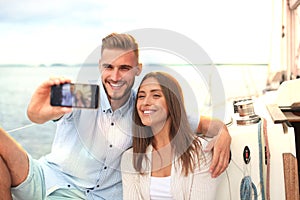 Happy couple in love taking selfie on sailing boat, relaxing on a yacht at the sea.