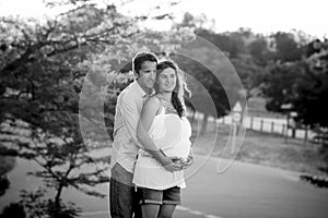 Happy couple in love together in park landscape on sunset with woman pregnant belly and man