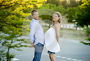 Happy couple in love together in park landscape on sunset with woman pregnant belly and man