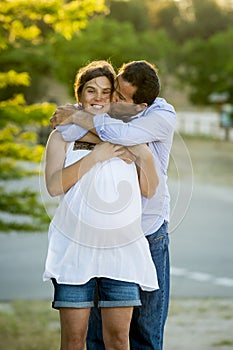 Happy couple in love together in park landscape on sunset with woman pregnant belly and man