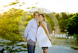 Happy couple in love together in park landscape on sunset with woman pregnant belly and man