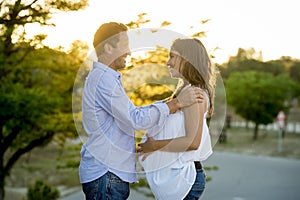 Happy couple in love together in park landscape on sunset with woman pregnant belly and man