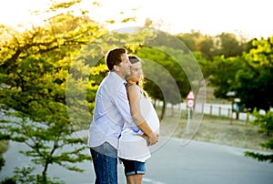 Happy couple in love together in park landscape on sunset with woman pregnant belly and man