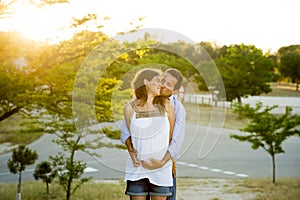 Happy couple in love together in park landscape on sunset with woman pregnant belly and man