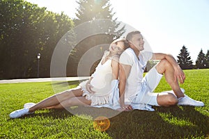 Happy couple in love waiting for child pregnancy hug in the summer park green trees sitting on the grass rest nature husband wife