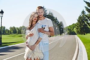 Happy couple in love waiting for child pregnancy hug walk in the summer park green trees nature husband and wife baby boy young