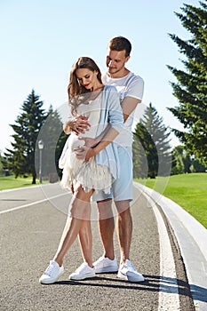 Happy couple in love waiting for child pregnancy hug walk in the summer park green trees nature husband and wife baby boy young