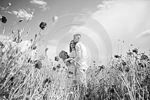 Happy couple in love walking in beautiful field of poppy flower on romantic day, wedding