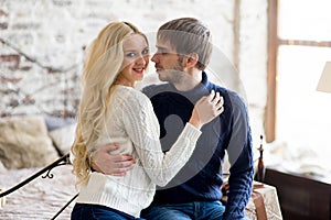 Happy couple of lovers in pullovers look each other sitting