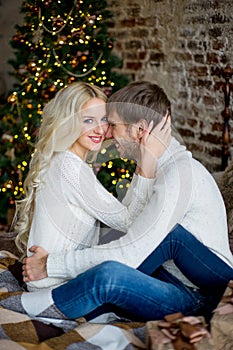 Happy couple of lovers in pullovers look each other sitting