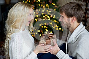 Happy couple of lovers in white pullovers give each other gifts