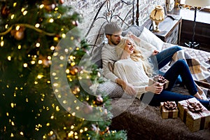 Happy couple of lovers in white sweaters give each other gifts