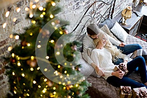 Happy couple of lovers in white sweaters give each other gifts