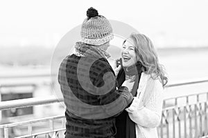 Couple loves walking around river. woman and man laughing on street. Man in woolen hat makes funny woman in knitted scurf photo