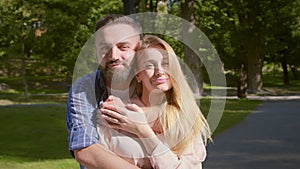Happy couple. Loving middle aged man and woman embracing and smiling to camera at park, slow motion