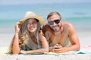 Happy couple lying at beach during sunny day