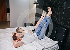 Happy couple lying on bed at home raising legs up. Carefree couple