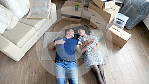 Happy couple lying down on their appartment floor