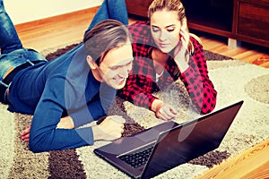 Happy couple lying on the floor with laptop