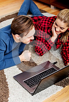 Happy couple lying on the floor with laptop