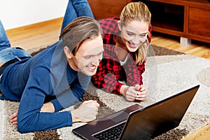 Happy couple lying on the floor with laptop