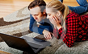 Happy couple lying on the floor with laptop