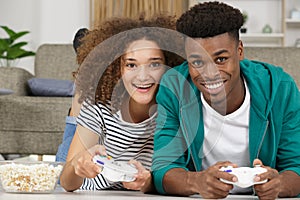 Happy couple lying on floor while playing video-games