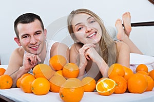 Happy couple lying with orange fruits