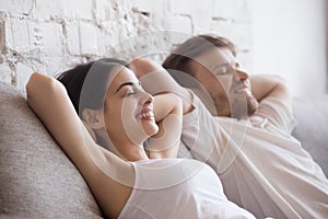 Happy couple lying relaxing on sofa with eyes closed