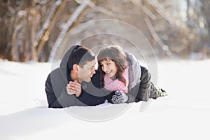 Happy couple lying on the snow and laughing