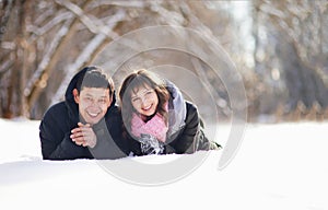 Happy couple lying on the snow and laughing