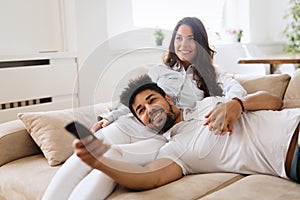 Happy couple lying on sofa together and relaxing at home