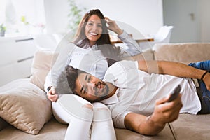 Happy couple lying on sofa together and relaxing at home