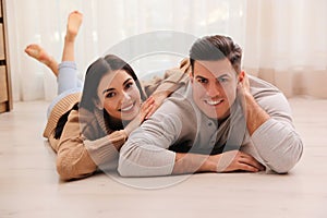 Happy couple lying on warm floor at home. Heating system