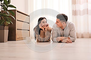 Happy couple lying on warm floor at home. Heating system