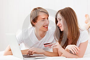 Happy couple makes online shopping with laptop and credit card a