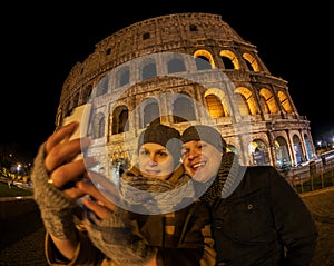 Happy couple making selfie by Coliseum at night