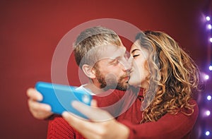 Happy couple making a selfie with mobile smartphone app - Young lovers having fun taking selfie with phone camera
