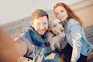 Happy couple making selfie photo with new pet dog retriever Labrador outdoors. Lifestyle summer walk concept