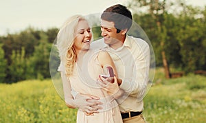 Happy couple, man proposing ring to his woman outdoors, wedding concept