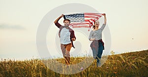 Happy couple man and woman with flag of united states enjoying the sunset on nature