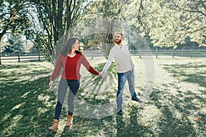 Happy couple man and woman in love walking in park outdoor. Lovely beautiful Caucasian heterosexual people dating walking on an