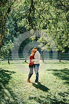 Happy couple man and woman in love walking in park outdoors. Lovely beautiful Caucasian heterosexual people hugging on autumn fall