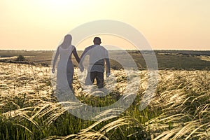 Happy couple man and woman in national Slavic clothes walking in field on sunset and holding hands. Welcome to Russia