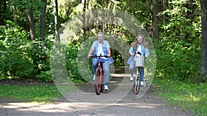 Happy couple man and woman ride bicycles in the park