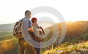 Happy couple man and woman tourist at top of mountain at sunset