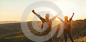 Happy couple man and woman tourist at top of mountain at sunset