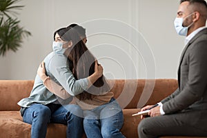 Happy couple in masks hugging reconciling at therapy session