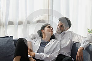 happy couple middle aged man and woman hugging lying relaxing on sofa in modern house living room. happiness man and woman